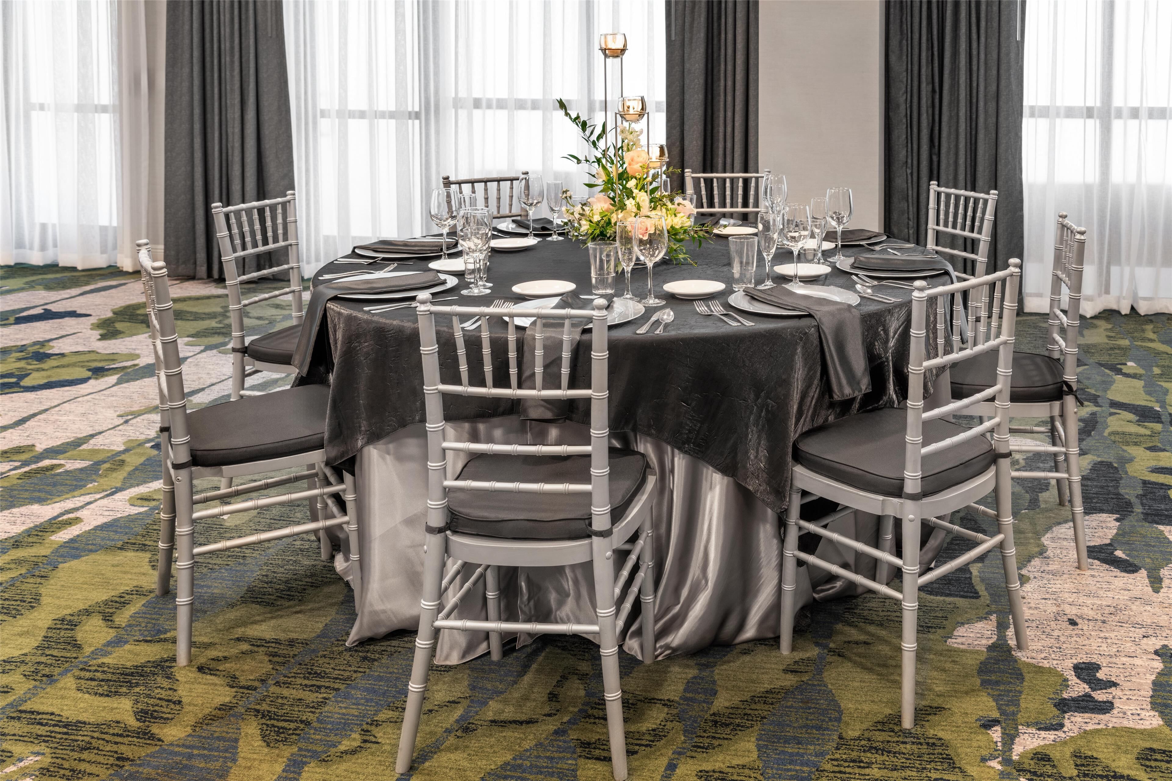 A round dining table set with chairs, a vase of flowers, and a chandelier.