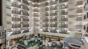 Een hotelatrium met meerdere verdiepingen, voorzien van balkons, zithoeken en beplanting.
