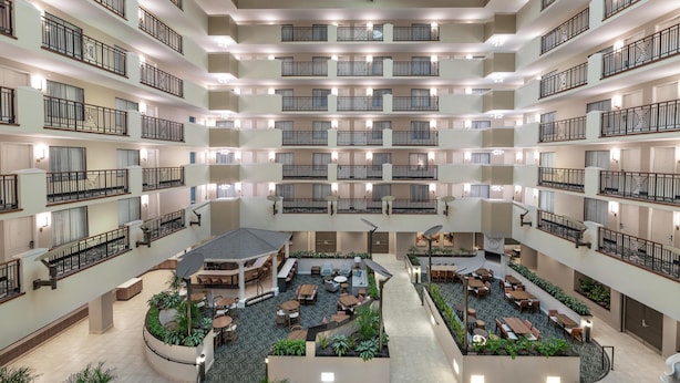Een hotelatrium met meerdere niveaus, voorzien van balkons, zitgedeeltes en een centrale binnenplaats.