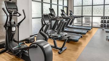 A gym with multiple treadmills, ellipticals, and a weight rack.
