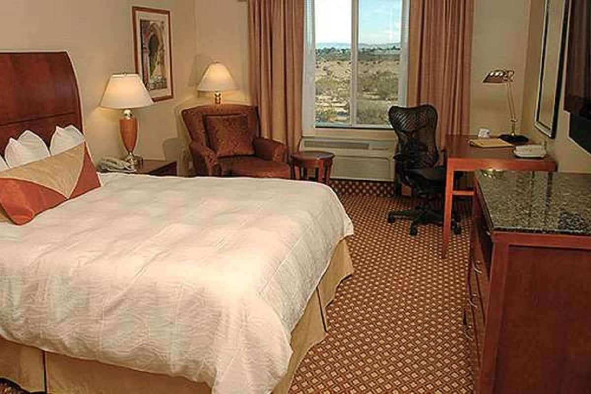Une chambre d’hôtel avec un grand lit, un bureau, une chaise et un téléviseur.