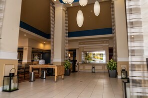 Een ruime lobby met een receptiebalie, een zithoek en potplanten.
