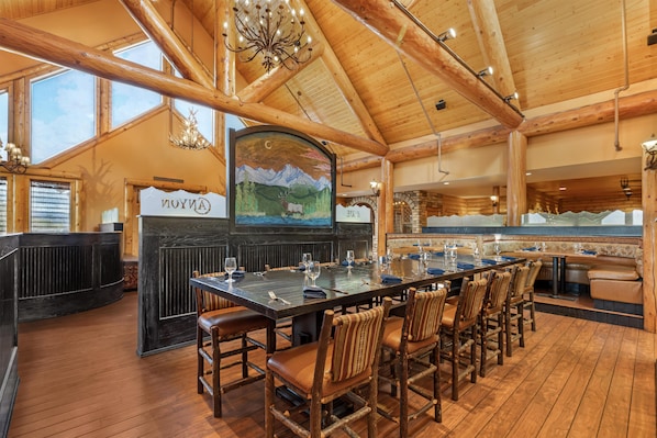 A wooden interior with a long dining table, chairs, and a chandelier. - Hilton Garden Inn Missoula (Missoula)