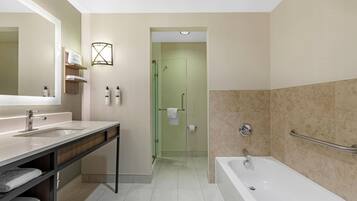 A modern bathroom with a large mirror, two sinks, a shower, and a bathtub.