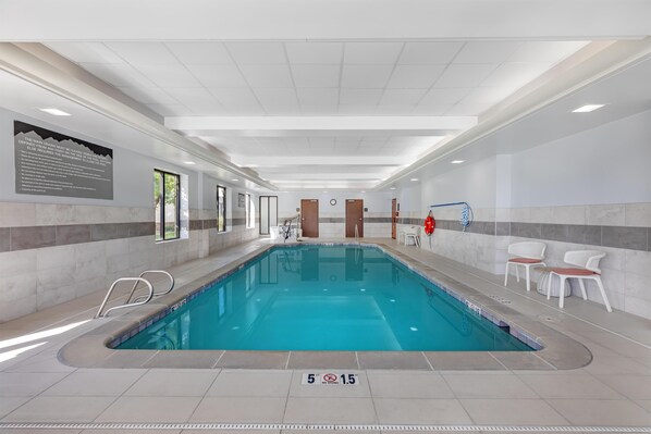 An indoor swimming pool with clear signage, a lifeguard chair, and a safety sign on the floor.
