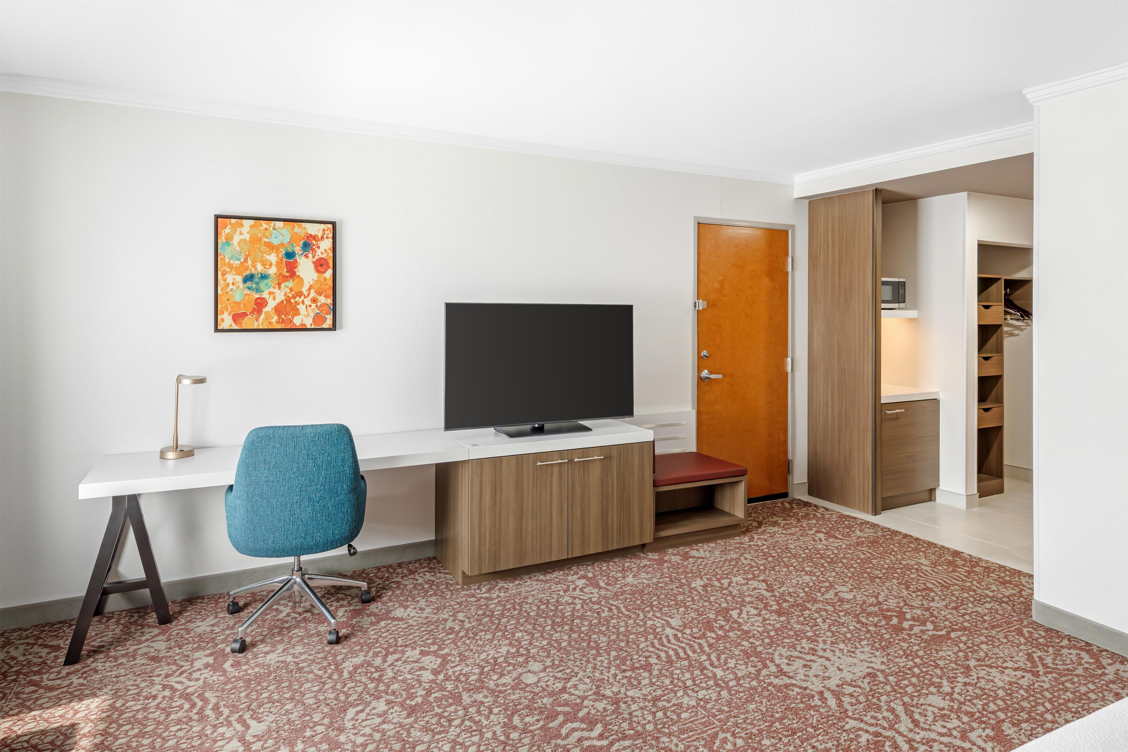 A modern room with a desk, chair, television, and a wardrobe.