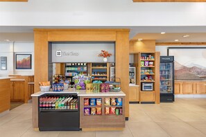 A snack kiosk with a variety of packaged goods, a refrigerated section, and a display of bottled beverages. - Hilton Garden Inn Missoula (Missoula)