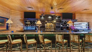 Eine Bar mit Holzwänden und -decken, mit einer Theke, Hockern und einem Fernseher darüber.