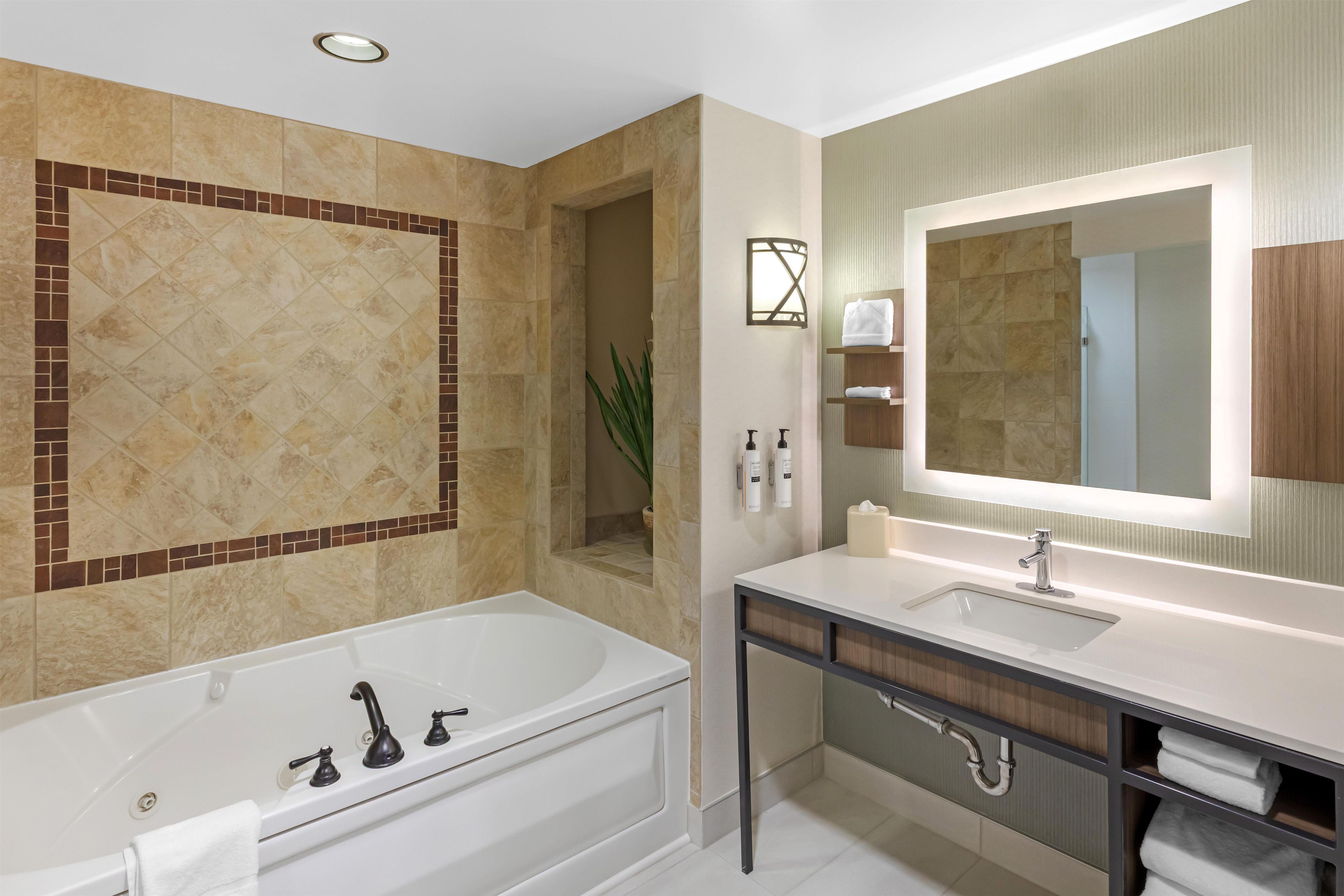 A modern bathroom with a bathtub, a sink, and a large mirror.