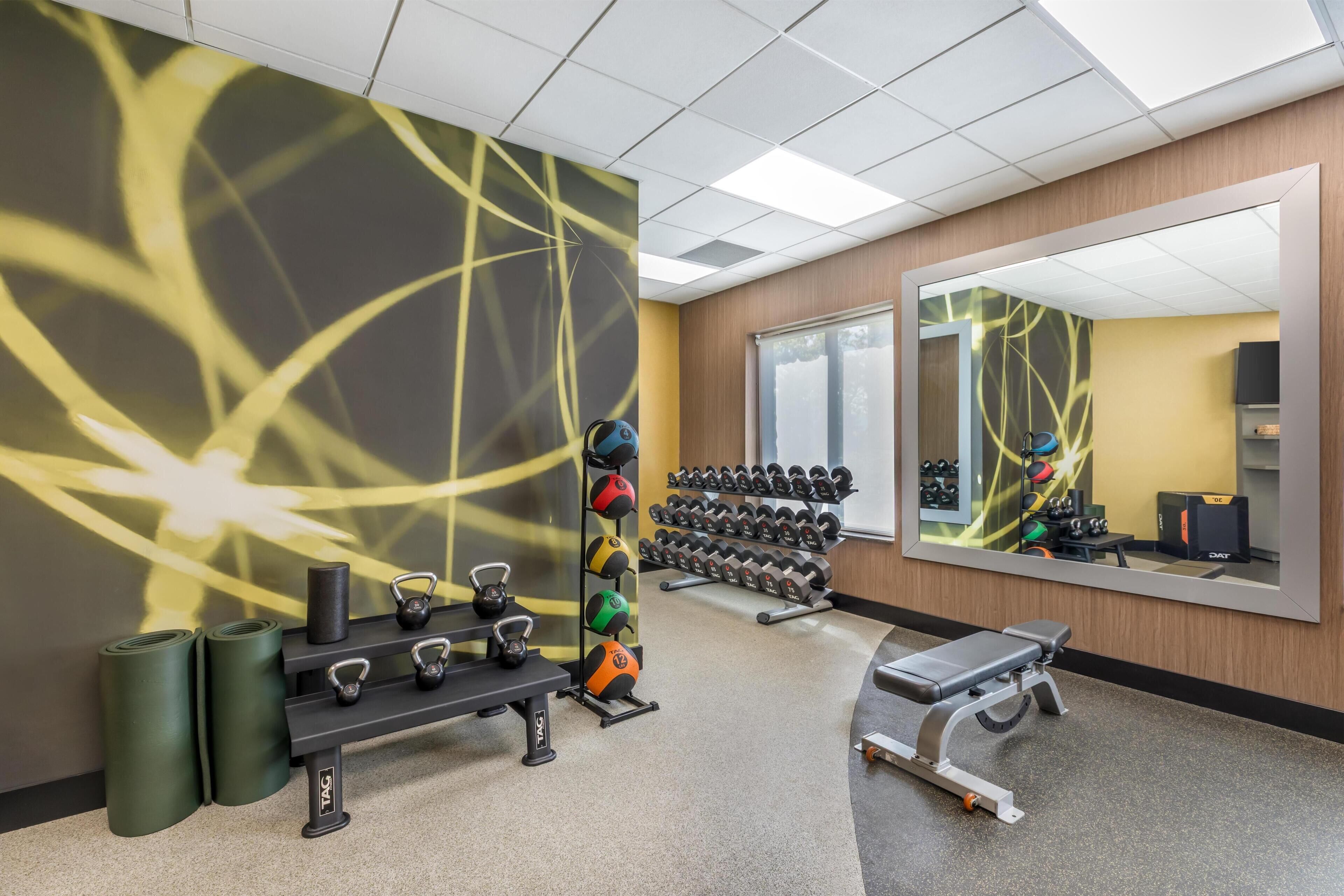 Une salle de sport équipée de matériel d’exercice, d’un banc et d’un miroir.