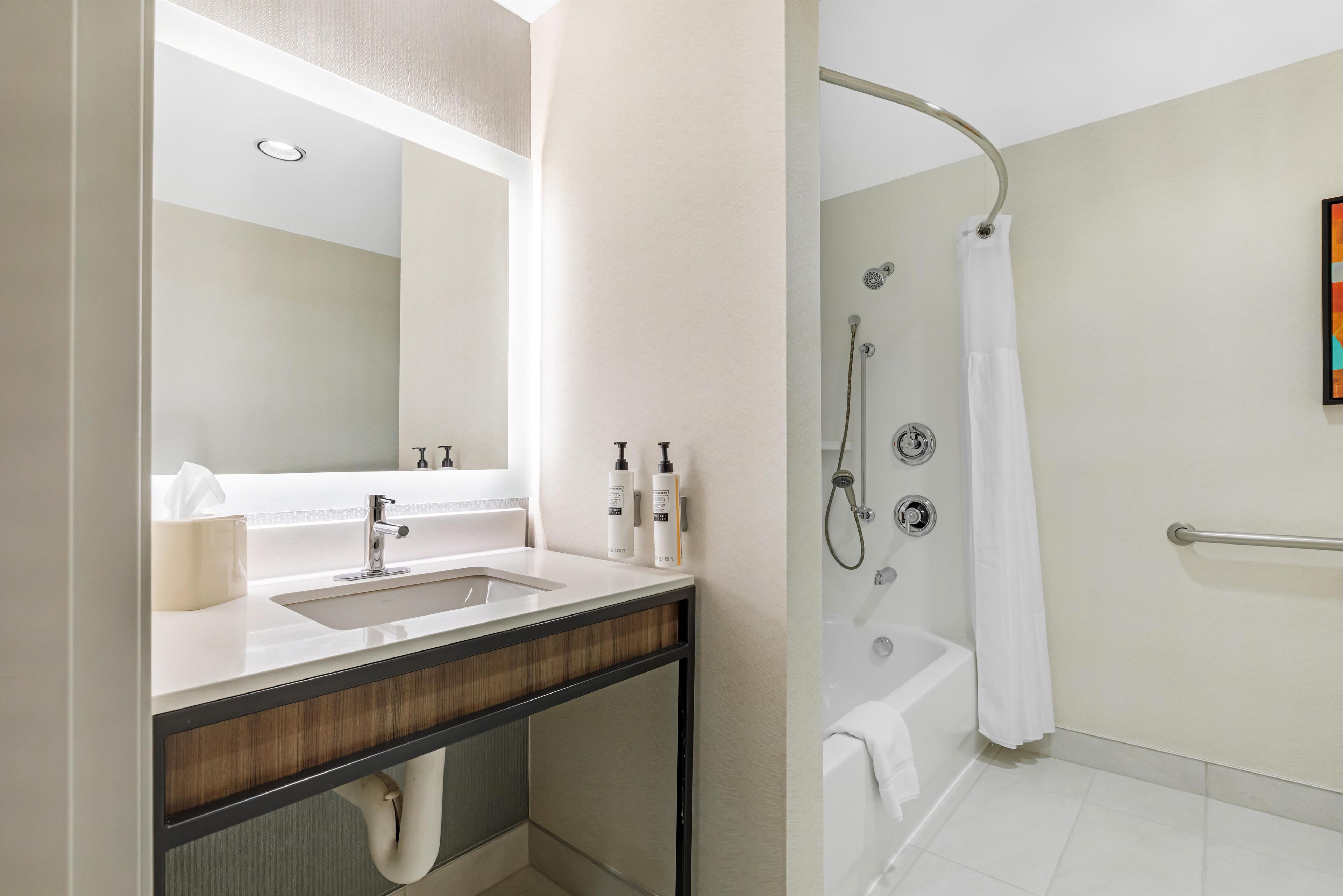 Un baño moderno con lavamanos, espejo y ducha.