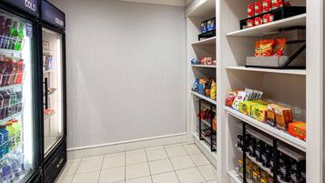 A clean, well-organized snack and beverage section in a store with a refrigerated area on the left and shelves stocked with various snacks and drinks on the right.