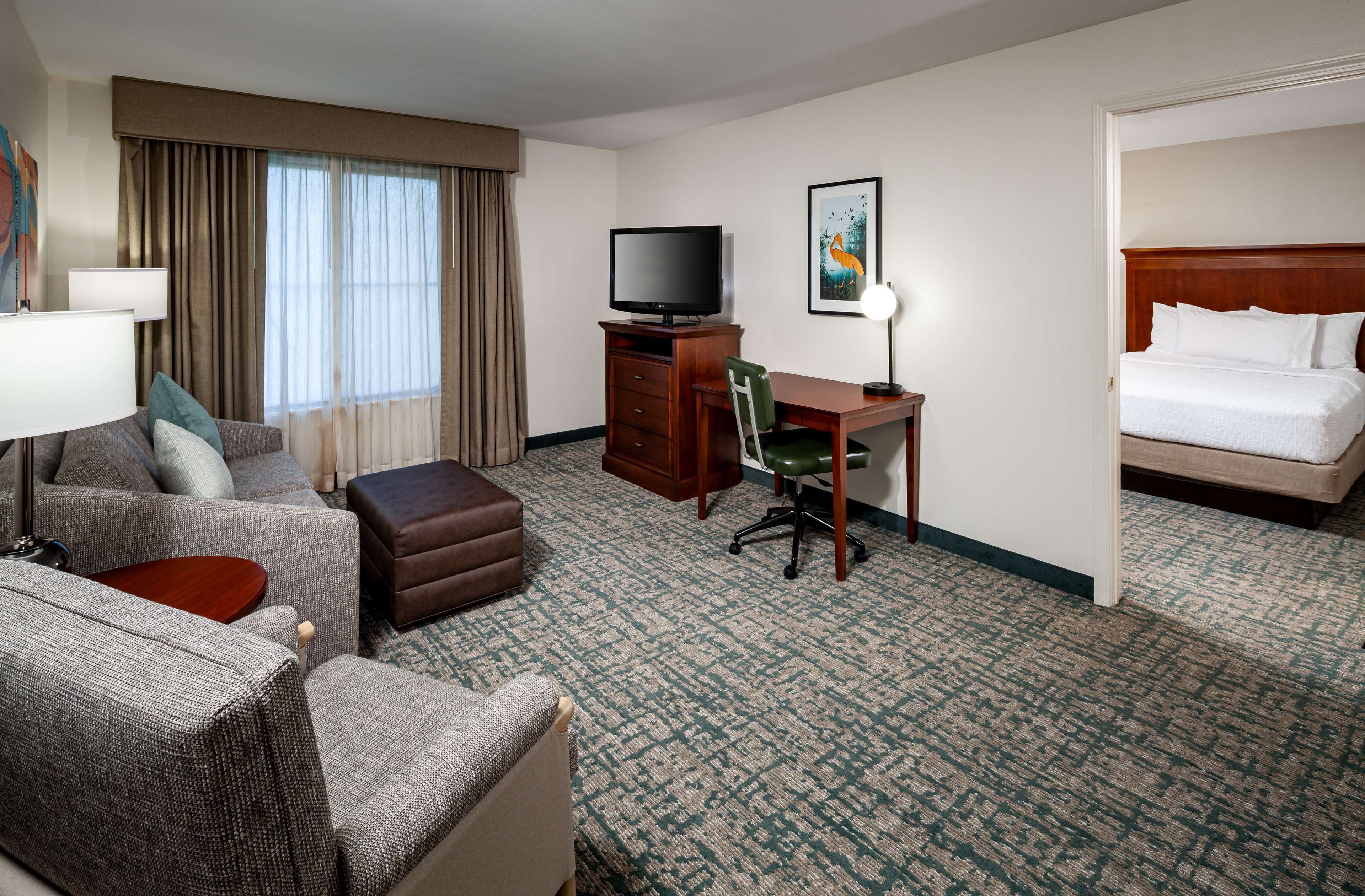 Habitación de hotel con sofá, escritorio, televisión, cama y piso alfombrado.