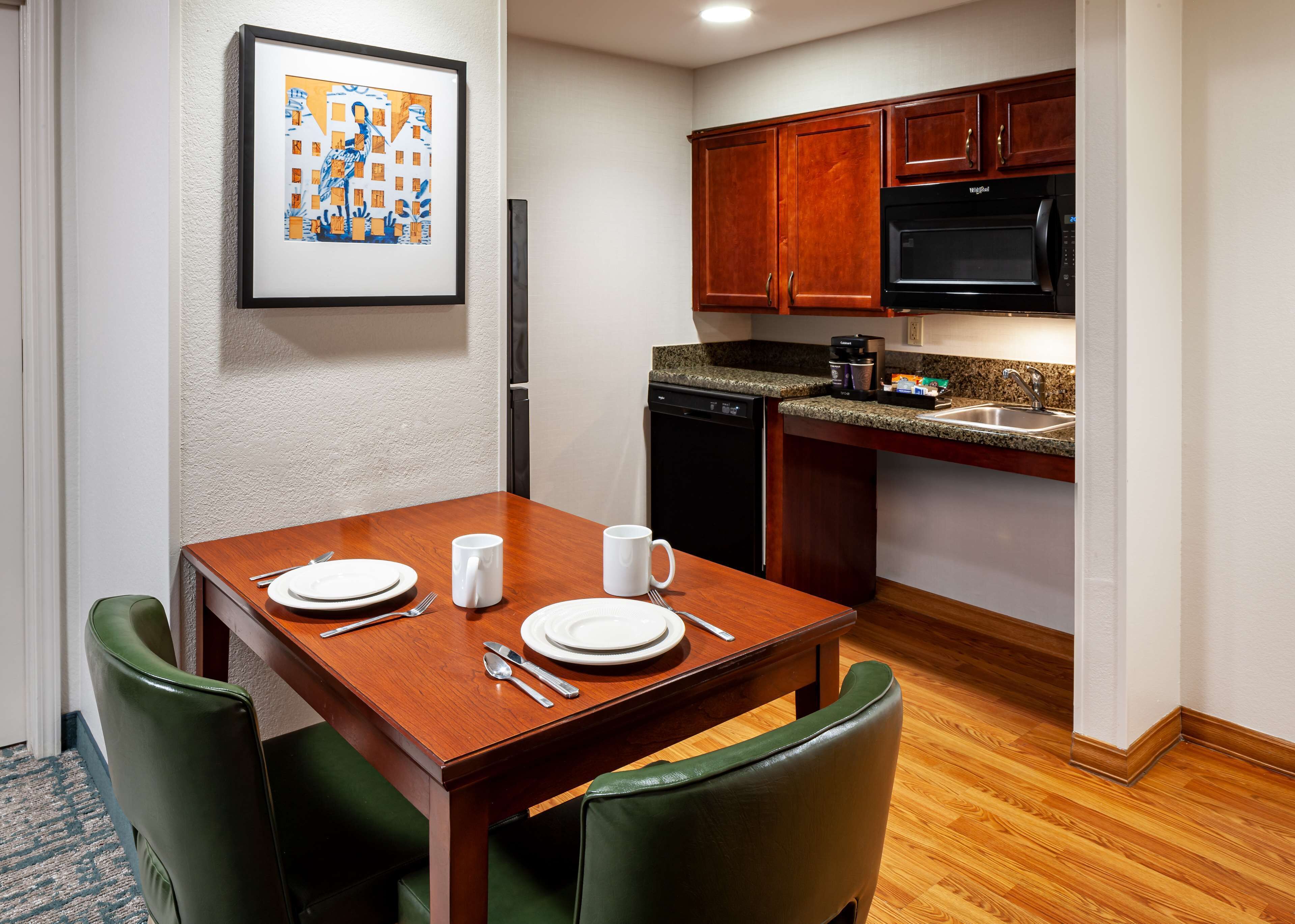 A compact kitchen with a dining table set for two, a microwave, and a coffee maker.