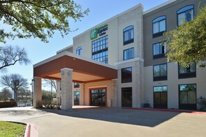 Ett Holiday Inn Express-hotell med en inglasad entré, flera fönster och en fasad av tegel.