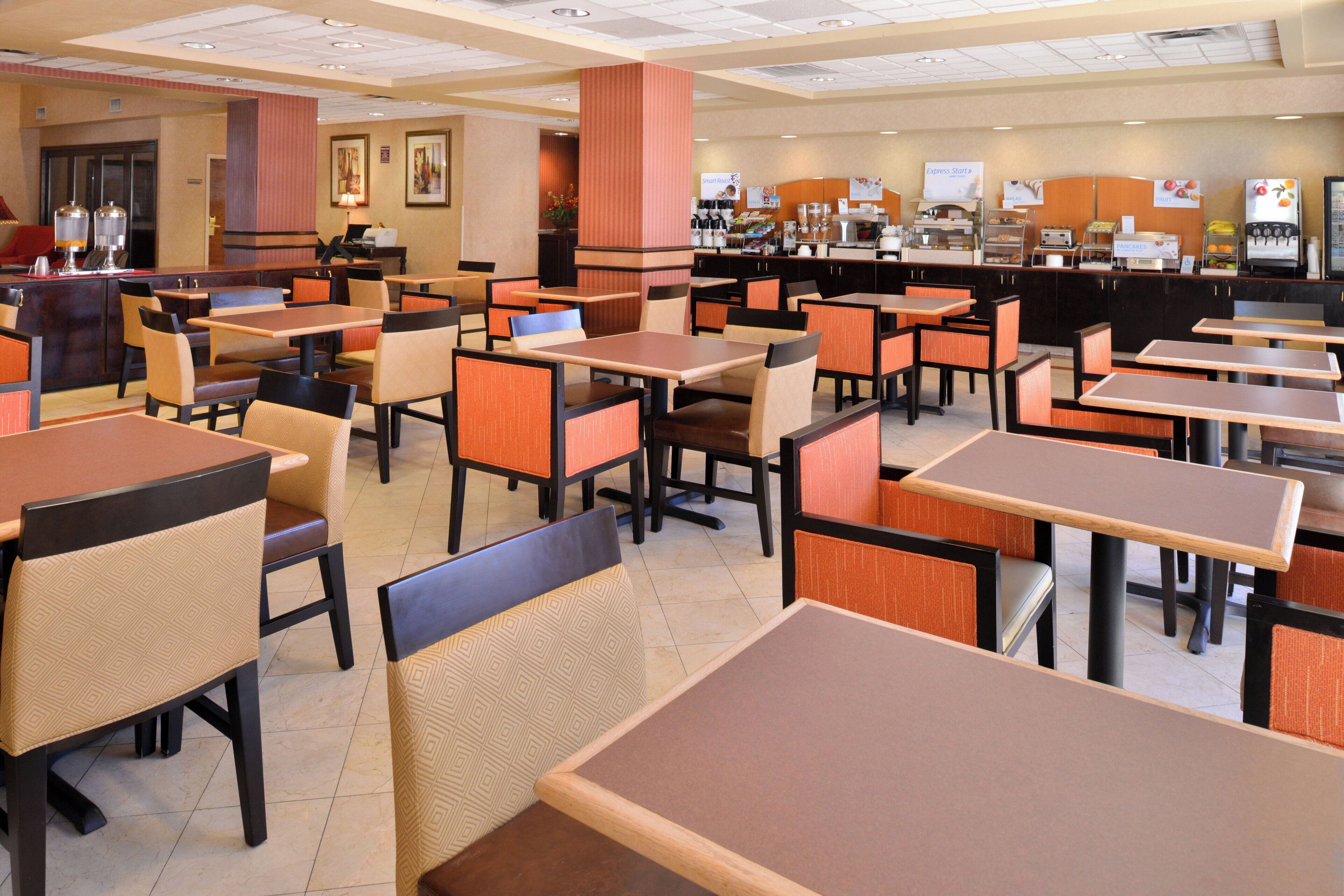 A spacious restaurant with multiple tables and booths, a counter with food and beverage options, and a clean, modern interior design.