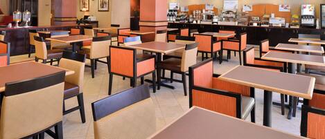 A spacious restaurant with multiple tables and booths, a counter with food and beverage options, and a clean, modern interior design.