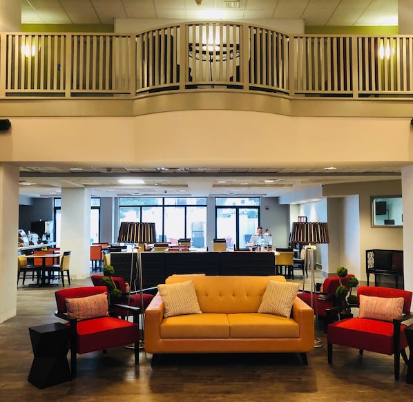 A spacious lobby with a central sofa, red chairs, and a high ceiling with a balcony. - Holiday Inn Express & Suites Austin North Central by IHG (Austin)