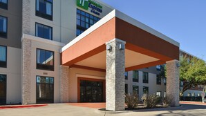 Ein Holiday Inn Express & Suites Hotel mit moderner Architektur, das einen markanten Eingangsbereich mit einer überdachten Passage und Steinsäulen aufweist.