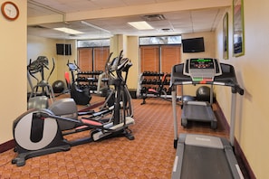 A gym with various exercise equipment, including treadmills, ellipticals, and weights.