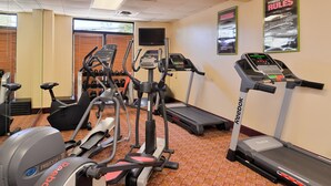 Ein Fitnessstudio mit Cardiogeräten, darunter Laufbänder, ein Crosstrainer und ein Indoorfahrrad.