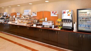 Ein Buffet mit verschiedenen Speisenstationen, darunter ein Saftautomat und eine Kühlvitrine.
