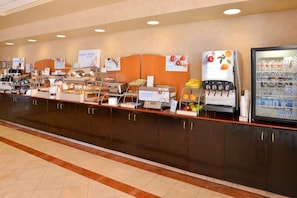 A buffet counter with various food stations, including a juice dispenser and a refrigerated display. - Holiday Inn Express & Suites Austin North Central by IHG (Austin)
