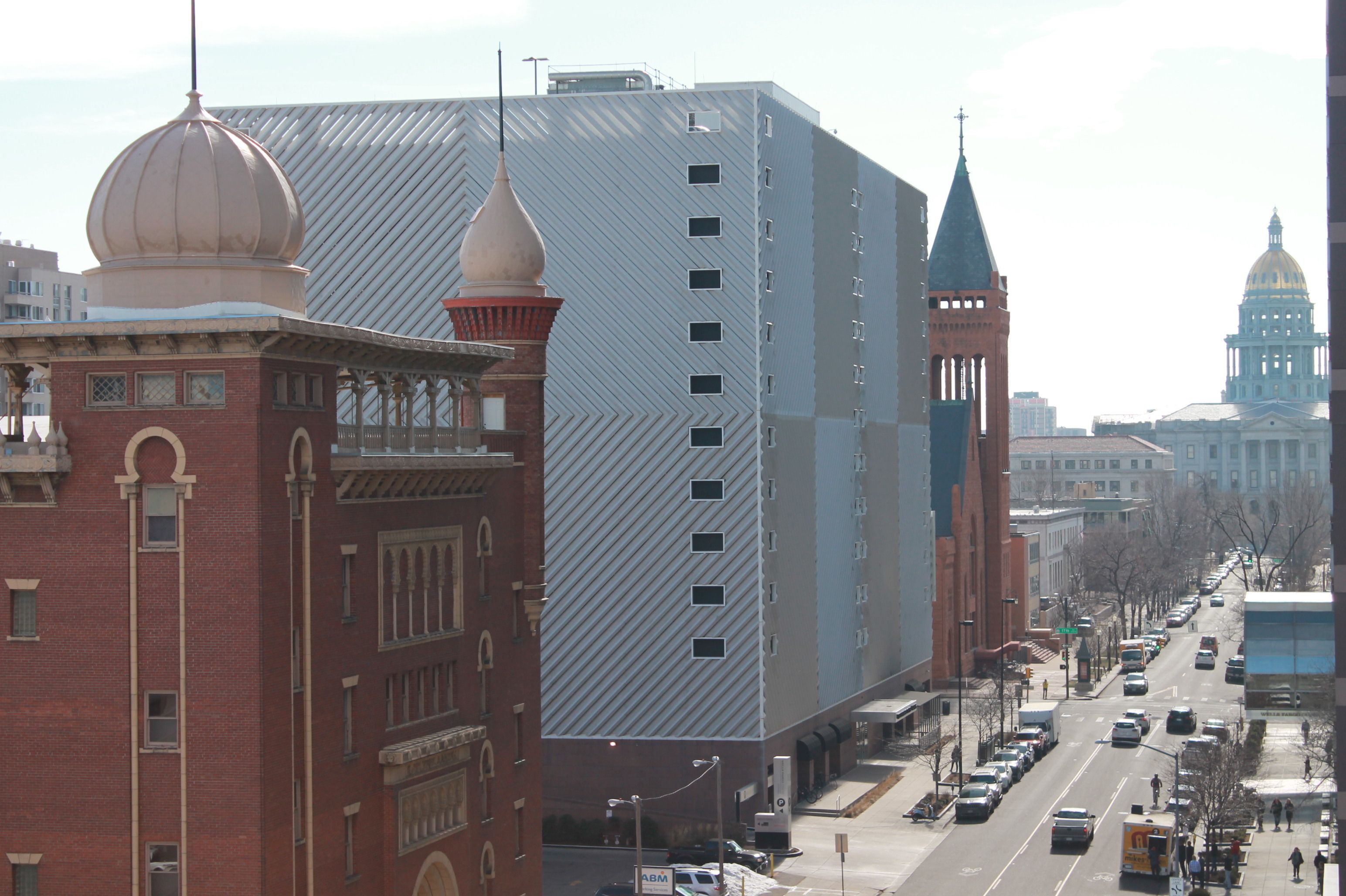 A cityscape with a mix of modern and historic architecture, including a prominent building with a patterned facade and a dome.