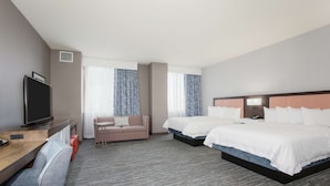 A hotel room with two beds, a desk with a television, a sofa, and a window with curtains. - Hampton Inn & Suites Denver-Downtown (Denver)