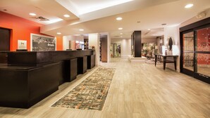 A hotel reception area with a dark reception desk, a patterned rug, and a wooden floor. - Hampton Inn & Suites Denver-Downtown (Denver)