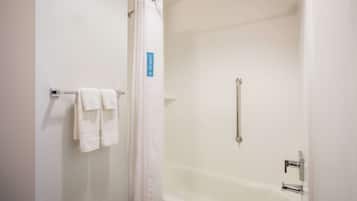 A bathroom with a bathtub, a shower curtain, and a towel rack with towels.