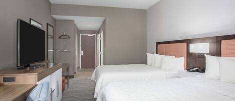 Habitación de hotel con dos camas, un escritorio con televisor, una lámpara y un teléfono.
