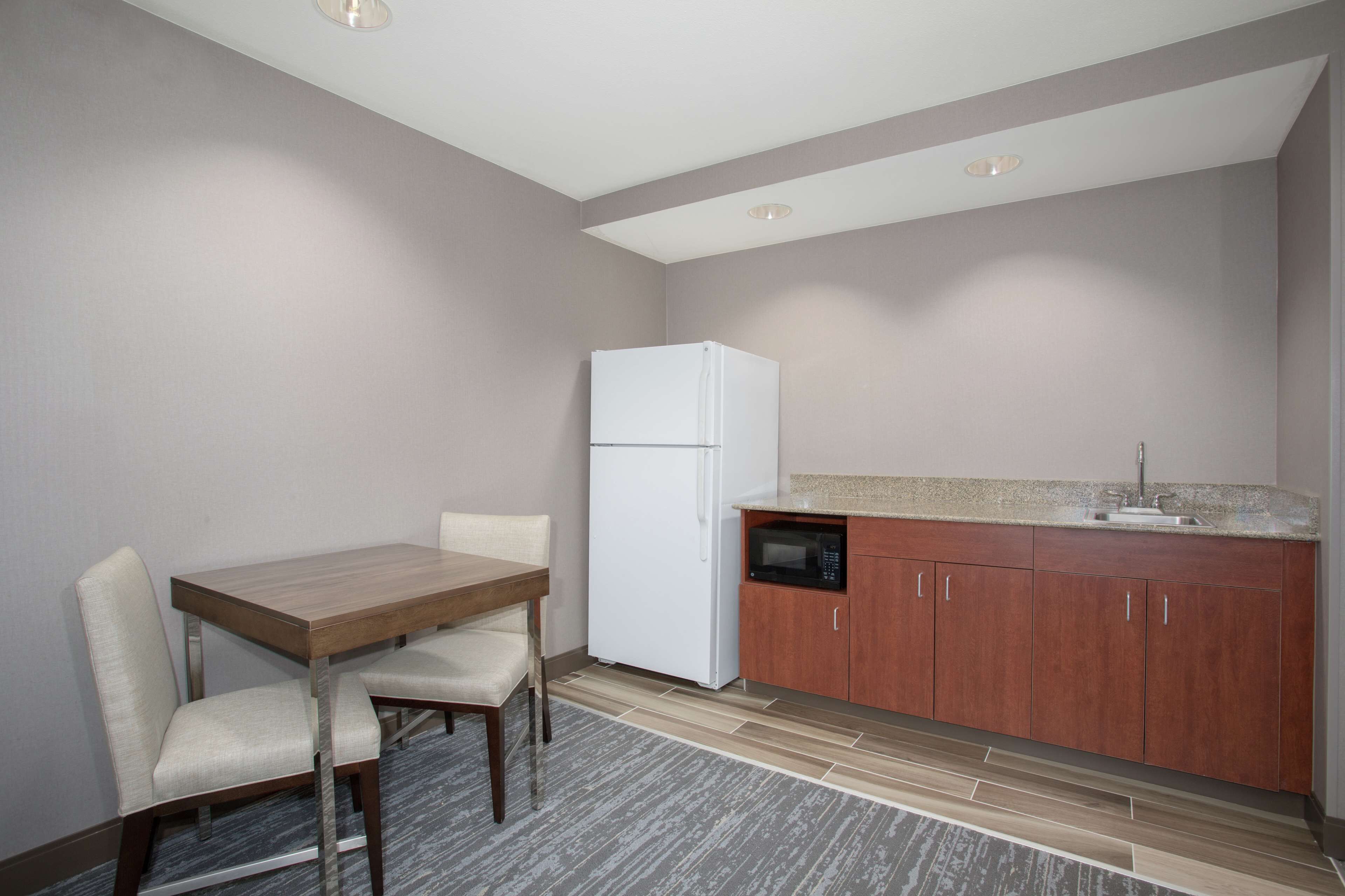 A compact kitchen with a refrigerator, microwave, and wooden cabinets.
