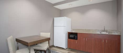 A compact kitchen with a refrigerator, microwave, and wooden cabinets.