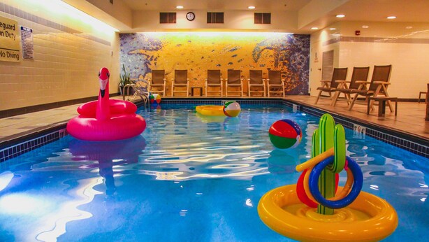 A swimming pool with inflatable toys, lounge chairs, and a mural on the wall. - Hampton Inn & Suites Denver-Downtown (Denver)
