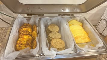 A buffet with three trays containing different food items.