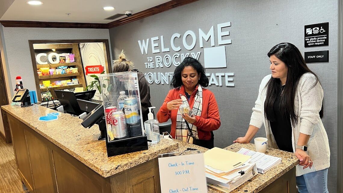 A reception area with a 'Welcome to Rocky Mountain State' sign, a counter with a 'Check-In Time 300 PM' sign, and a 'Staff Only' sign.