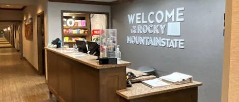 A reception desk with a 'Welcome to the Rocky Mountain State' sign, a reception area, and a wooden floor.