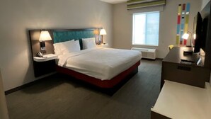 Une chambre d’hôtel avec un grand lit, des tables de chevet, un bureau, une chaise, une télévision et une fenêtre.