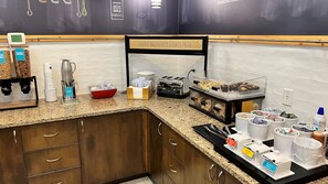 A breakfast bar with coffee machines, a toaster, and various food containers.
