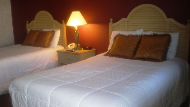 Two single beds with white linens, a nightstand with a lamp, and a telephone.