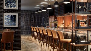 A bar area with multiple stools, a brick wall, and a shelf with vintage sewing machines.