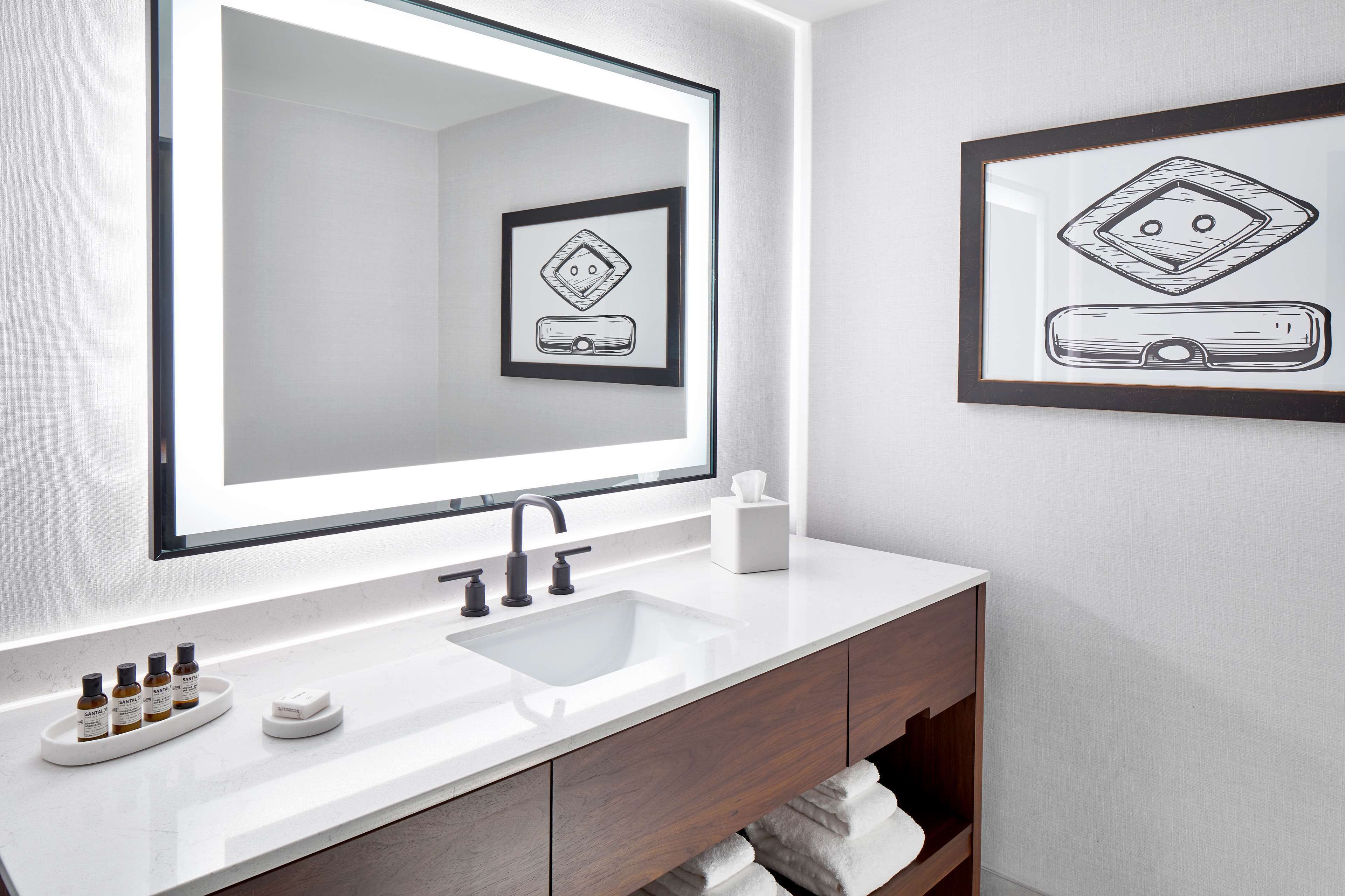 A modern bathroom with a large mirror, a sink, and a vanity with a towel rack.