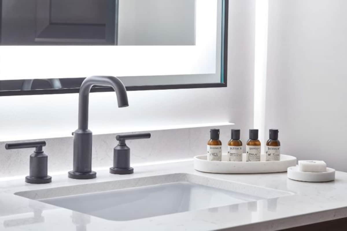 A modern bathroom with a large sink, a mirror, and a window.