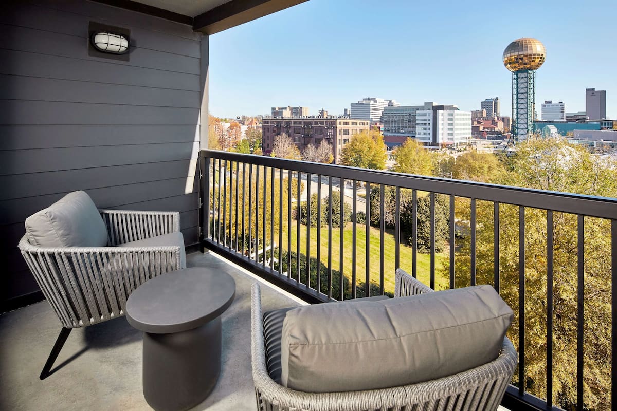 A balcony with wicker furniture and a view of a cityscape including a distinctive tower.