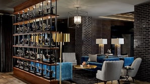 A modern living room with a blue sofa, two armchairs, a coffee table, and a large wooden bookshelf filled with decorative items.