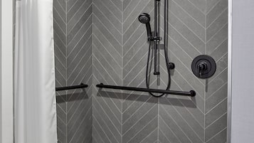 A modern shower area with a rain showerhead, handheld showerhead, and a towel rack.