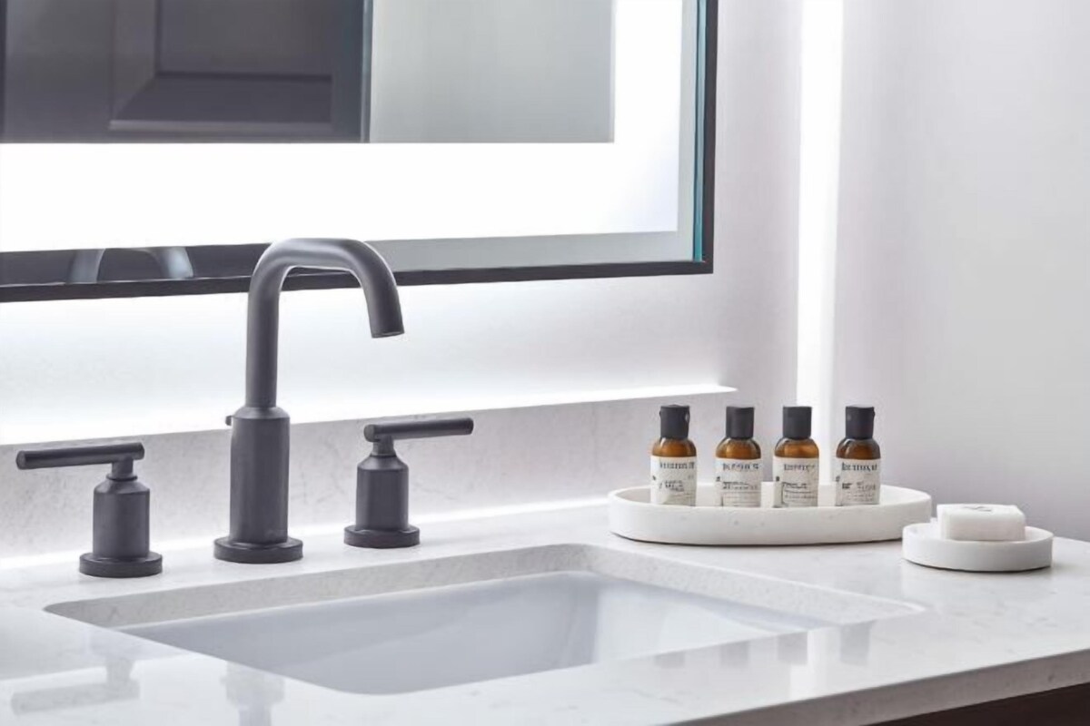 A modern bathroom with a large sink, a mirror, and a window.