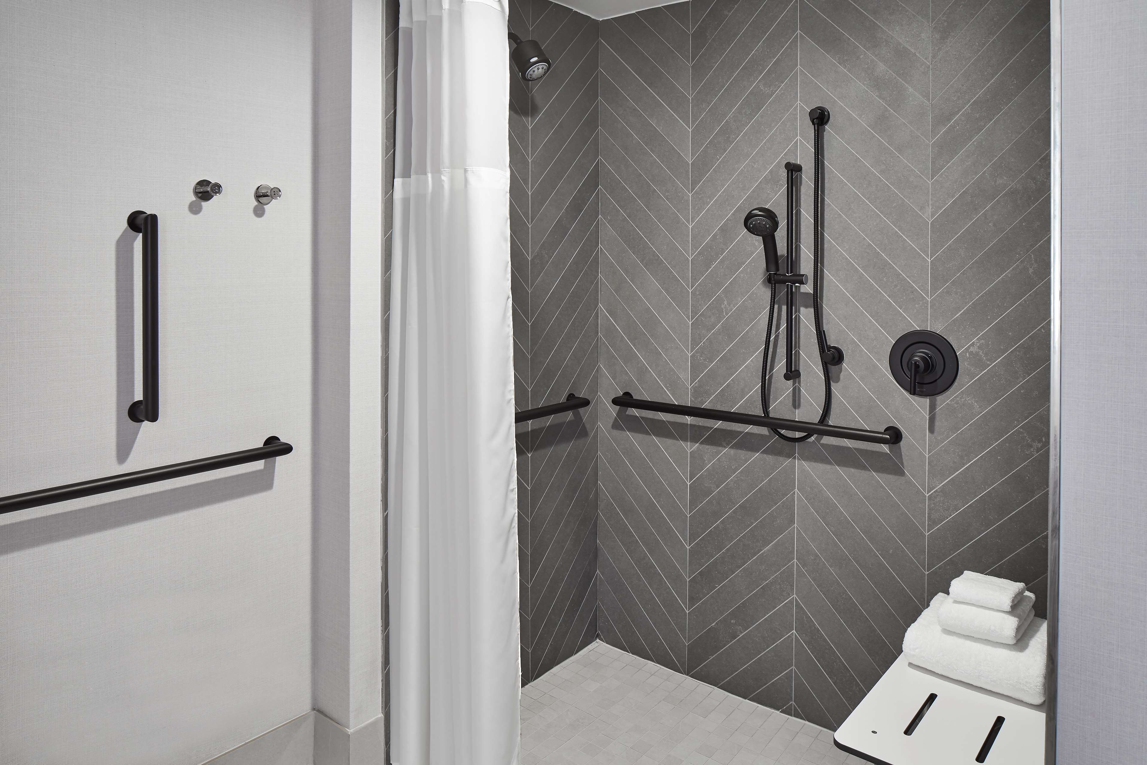 A modern bathroom with a shower, toilet, and towel rack.