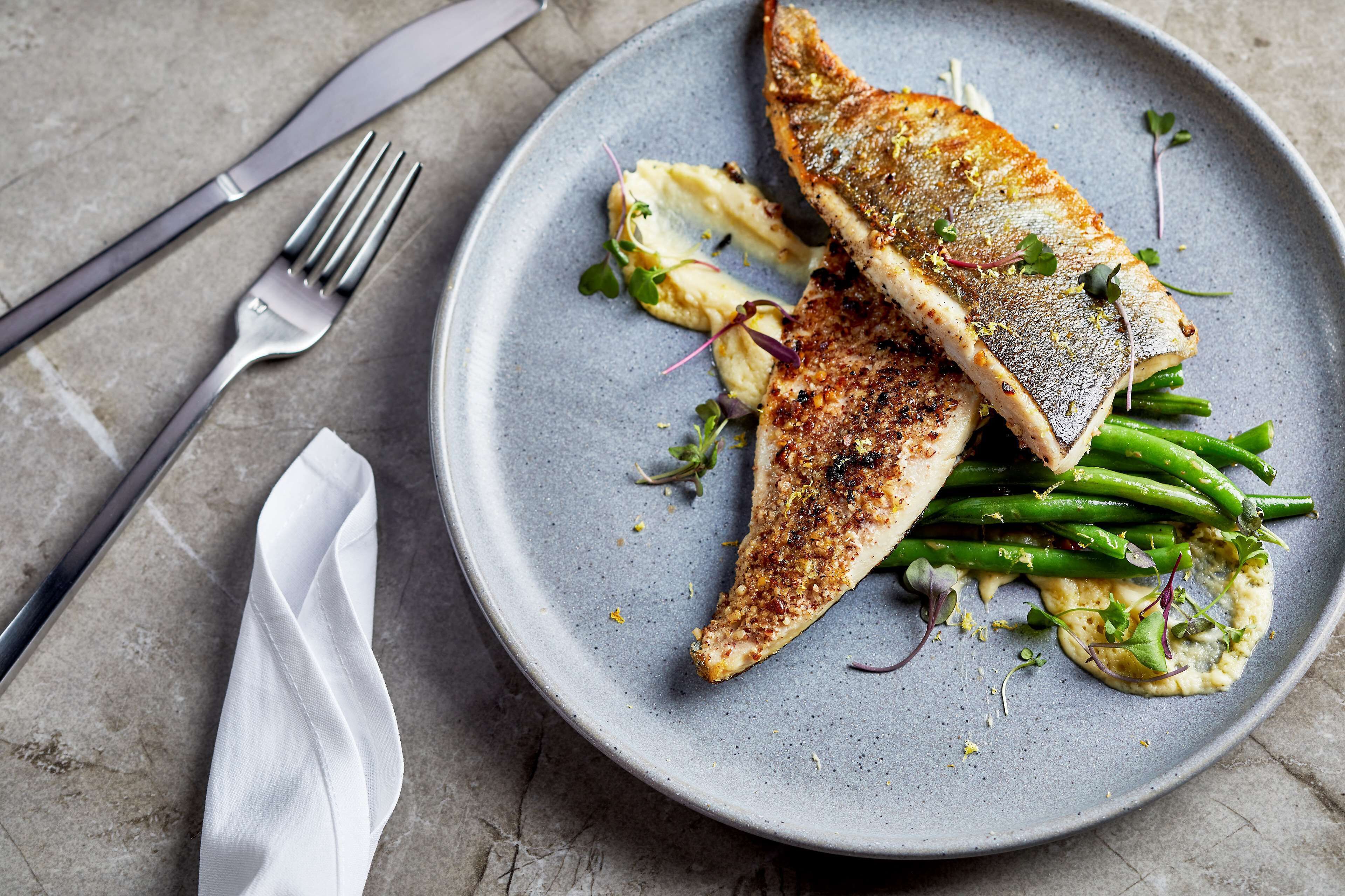 A plate with grilled fish, green beans, and a side salad on a gray plate.